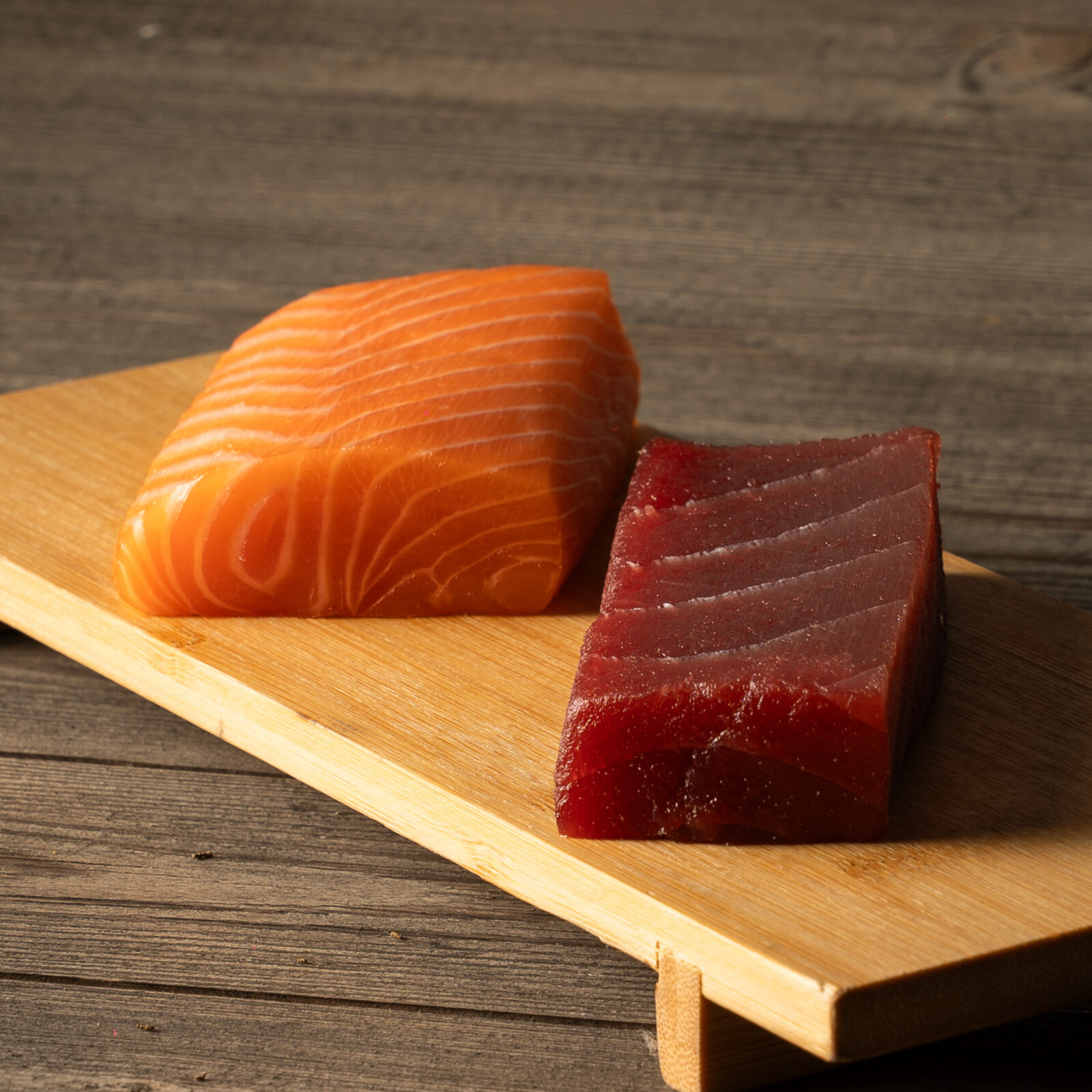 Filetti di salmone e tonno crudo su tagliere, materia prima Nami